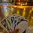 A hand holding a set of colorful cards with numbers and symbols, set in an indoor environment decorated with warm yellow string lights and a blurred background of various objects.